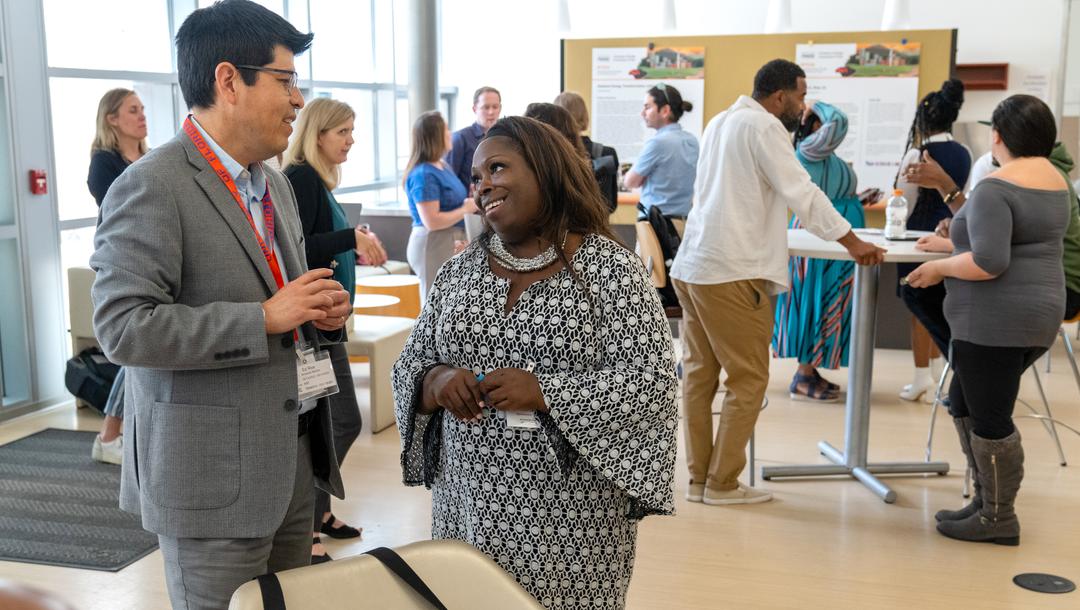 Two people talking at an event with other people in the background